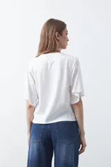 Remera blanca de manga corta con bordado frontal en azul que dice "dolce far niente the sweetness of doing nothing". Tiene un calce relajado.