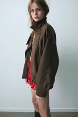 Cazadora de paño en color marrón, con cuello subido, cierre frontal cruzado con botones y cremallera, bolsillos laterales de vivo y bajo elástico.