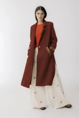 Tapado largo color ladrillo con solapas, cierre con botón y bolsillos laterales con solapa de cuero marrón.