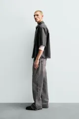Sobrecamisa de corte relajado confeccionada en tejido efecto piel, con cuello solapa, manga corta y cierre frontal con cremallera. Presenta un bolsillo plastrón en el pecho y bajo con aberturas laterales.
