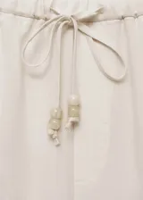 Pantalón de lino color beige, de corte recto y diseño relaxed con cintura elástica y cordón ajustable.