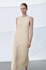 Vestido midi de viscosa con efecto arrugado, cuello redondo y diseño sin mangas. Presenta una sobrecapa superior con bordados detallados y entredoses, con cordones laterales ajustables terminados en borlas.