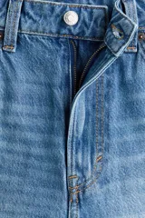 Jeans de denim rígido de algodón en color celeste con lavado deslavado. Presentan diseño de tiro alto, 5 bolsillos, cierre de cremallera y botón, y corte holgado tipo baggy con pierna recta y amplia desde el muslo hasta el dobladillo.
