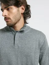 Sweater de punto color tostado, con cuello alto y cierre frontal parcial con botones. Diseño de manga larga con puños y ruedo acanalados.