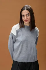 Sweater de tejido de punto color gris con cuello redondo y paneles de cuero sintético en color blanco en los hombros.