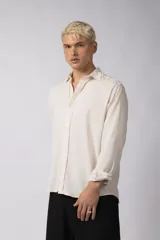 Camisa de manga larga con cuello clásico y cierre frontal de botones. Presenta un calce relajado y una textura liviana.