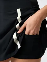 Skort deportivo negro con short interior integrado, cintura alta y franjas verticales blancas en los laterales. Confeccionado con tecnología Aloe Vera.