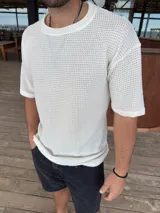 Remera de tejido de punto con textura calada, color blanco, de corte oversize y manga corta.
