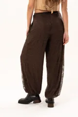 Pantalón tipo babucha de encaje color chocolate, con forro interior, cintura regulable y elásticos en los tobillos que generan una silueta abuchonada.