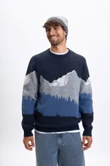 Buzo de punto con cuello redondo y diseño estampado de paisaje montañoso en tonos azules, grises y blancos. Presenta puños y ruedo acanalados.