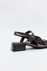 Sandalia negra de cuero sintético con textura símil reptil, taco medio cuadrado y múltiples tiras con hebillas metálicas ajustables.