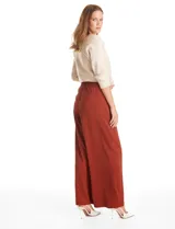 Pantalón tipo palazzo de corte ancho y fluido, confeccionado en tejido sastrero. Presenta tiro alto con doble abotonadura frontal, pinzas decorativas y cintura elástica en la parte posterior. Incluye bolsillos laterales funcionales.