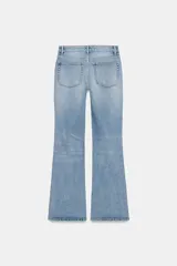 Jeans de denim azul oscuro con efecto desgastado y lavado, tiro bajo, corte bootcut y bajo flare. Presenta cinco bolsillos y cierre frontal con cremallera y botón.