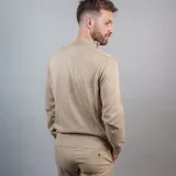 Buzo de punto color beige con cuello alto y medio cierre frontal.