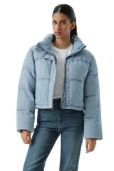 Campera puffer corta de denim en color azul claro lavado, con cuello alto, cierre frontal y botones a presión. Diseño acolchado con costuras horizontales.