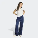 Pantalón deportivo Adidas SST de satén color azul marino, de corte holgado y diseño de pernera ancha. Cuenta con las clásicas tres tiras blancas a lo largo de los laterales y el logo del trifolio bordado en una pierna.