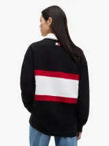 Chomba de rugby de manga larga Tommy Hilfiger en colaboración con Cadillac Formula 1 Team. Presenta un diseño en bloques de color negro, blanco y rojo, con cuello estilo rugby en color blanco y cierre frontal oculto. Incluye el logo de Cadillac en fuente script y el logo de Tommy Hilfiger estampados en el pecho.