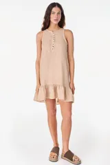 Vestido corto lila de lino, sin mangas, con escote redondo, cartera de botones de nácar en el frente y volado fruncido en el ruedo.