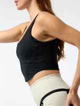 Top deportivo negro de corte crop, con costuras visibles de inspiración corsetera en el pecho, tirantes anchos y espalda rebajada.