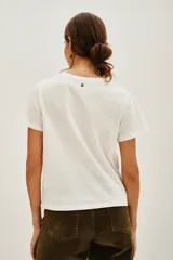 Remera de algodón color blanco con cuello redondo y mangas cortas con dobladillo. Presenta un bordado detallado de una mariposa en tonos dorados en la parte frontal.