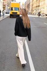 Jersey de punto negro, con cuello en V (pico) y manga larga, acabado en rib en puños, cuello y bajo.