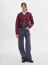 Pantalón jean de tiro alto y corte pinzado, con perneras de caída suelta y levemente anchas en el bajo. Posee pasador con hebilla en la parte trasera.
