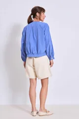 Cazadora azul de manga larga con puños elásticos, cuello redondo sin solapas y cierre frontal con botones grandes de color claro.