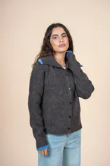 Cardigan de tejido con relieve en color gris oscuro, con cuello camisero y puños en contraste de color azul. Presenta cierre frontal con botones y un calce relajado.