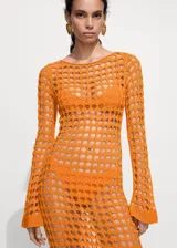 Vestido largo de punto calado color naranja, con cuello redondo y mangas largas acampanadas. Diseño de tejido abierto con textura geométrica.
