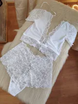 Conjunto de lencería compuesto por un top de encaje con mangas cortas y escote profundo, y una bombacha tipo hipster de encaje completo.