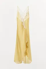 Vestido midi de georgette en color amarillo, con escote en pico y tirantes finos dobles cruzados en la espalda. Presenta detalles de encaje en contraste, bajo asimétrico con abertura frontal y volantes.
