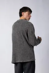 Buzo de corte oversize confeccionado en tela waffle de algodón con proceso de teñido acid wash. Presenta cuello redondo con detalle de costura en X y mangas largas con puños acanalados.