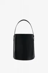 Cartera tipo tote de cuero vacuno negro con acabado pulido, diseño cilíndrico rígido y asa superior firme.