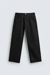 Jeans de corte recto y ajuste holgado, confeccionados en denim de algodón rígido color negro. Presentan diseño de cinco bolsillos, tiro medio y cierre frontal con cremallera y botón.