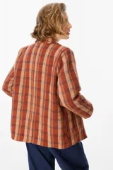 Blazer de corte recto con estampado de cuadros en tonos marrones, beige y rojos. Presenta solapas clásicas, cierre frontal con un botón y bolsillos laterales con solapa.