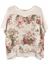 Blusa de lino color blanco con estampado floral en tonos rosados y grises, escote redondo y mangas cortas holgadas.