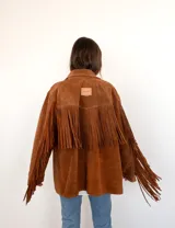 Blazer marrón de gamuza con flecos en la espalda y mangas largas.