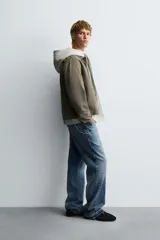 Sobrecamisa de denim de algodón negro con efecto lavado, corte relajado (relaxed fit). Presenta cuello solapa, cierre frontal con cremallera, manga larga con puño abotonado y bolsillo plastrón en el pecho.