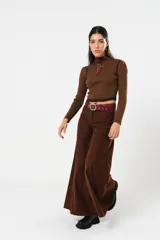 Pantalón marrón acampanado de tiro medio, con bolsillos delanteros y traseros. Cierre frontal con cremallera y botón.