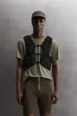 Chaleco deportivo técnico color verde con detalles en marrón, múltiples bolsillos con cierre y ajuste lumbar con cordón elástico.