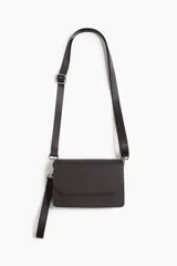 Cartera bandolera de diseño minimalista con solapa y cierre magnético. Incluye una correa larga ajustable y extraíble, además de una correa de muñeca adicional. Presenta una textura fina y acabado mate.