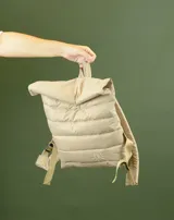 Mochila acolchada color beige con cierre superior enrollable y hebilla.