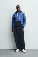 Sudadera hoodie regular fit de color azul, con capucha y bolsillo canguro negro. Cuenta con cordones ajustables blancos y detalles en color negro en la capucha, el bolsillo y los puños.