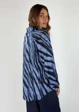 Blusa azul con estampado de cebra en negro, escote en V y mangas largas abullonadas.