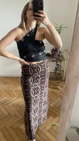 Top negro con diseño cruzado en el frente, estilo halter y con detalles de tachas doradas.