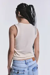 Musculosa color crudo de tejido estriado, con cuello redondo y sisas decoradas con tachas metálicas plateadas.