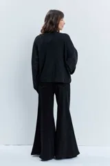 Bomber de punto color negro con apliques de strass brillantes, cuello redondo, cierre frontal con botones y mangas largas.