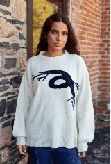 Sweater de punto color blanco con diseño de raíces en color azul marino en el frente, de corte holgado, cuello redondo y mangas largas con puños ajustados.