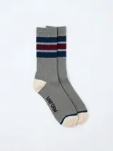 Medias de caña media color gris, con diseño de rayas horizontales en azul y bordó en la parte superior. Presentan puntera y talón en color crema con detalles en azul, y la palabra 'UNIFORM' estampada en el lateral.