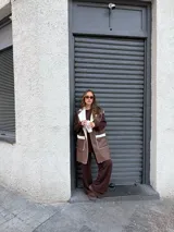 Chaleco largo de eco cuero color marrón con interior y detalles de corderito en solapas y bolsillos frontales.